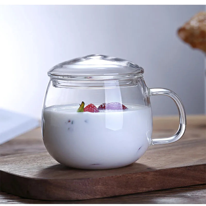 Clear glass mug with handle and lid on a wooden surface