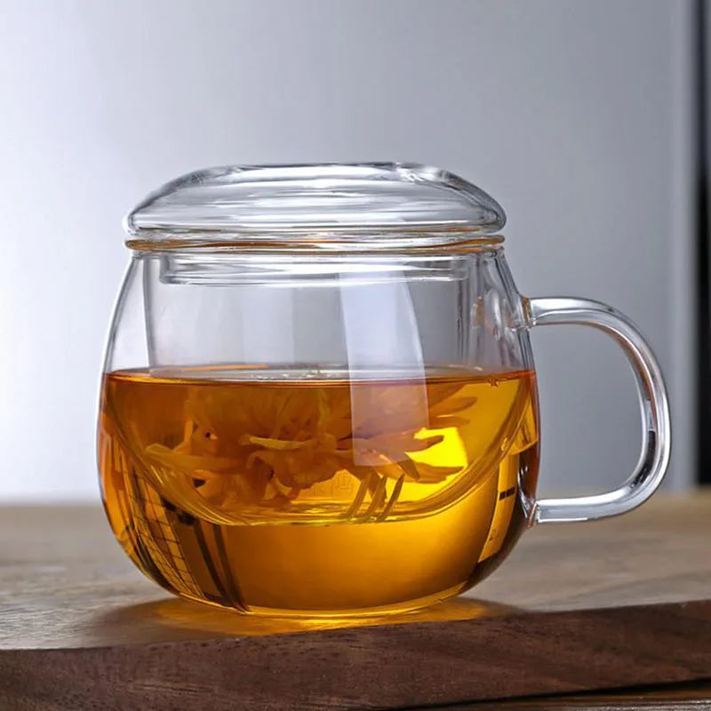 Clear glass mug with handle filled with hot tea on a wooden surface.