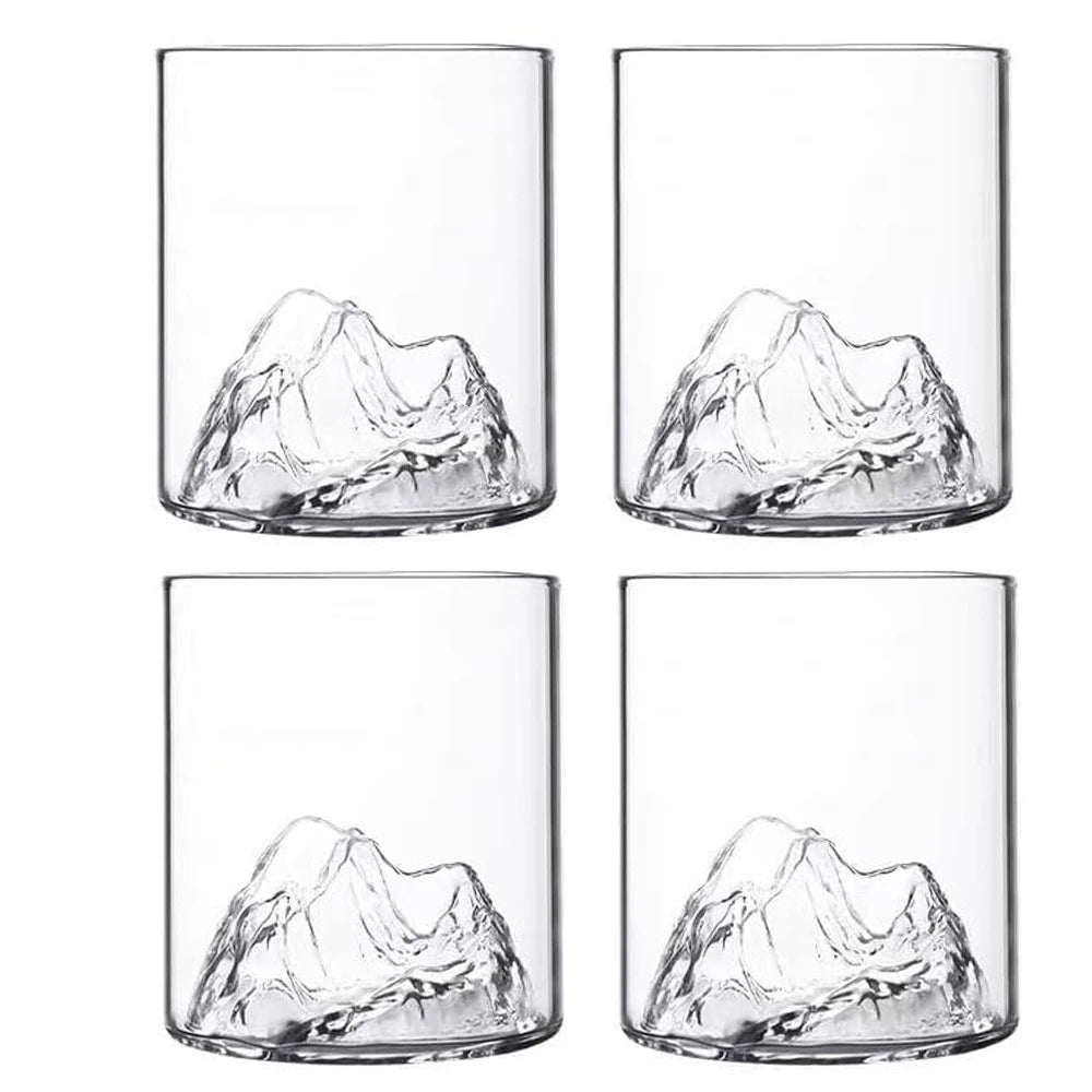 Four clear glass tumblers with mountain-like designs on a white background