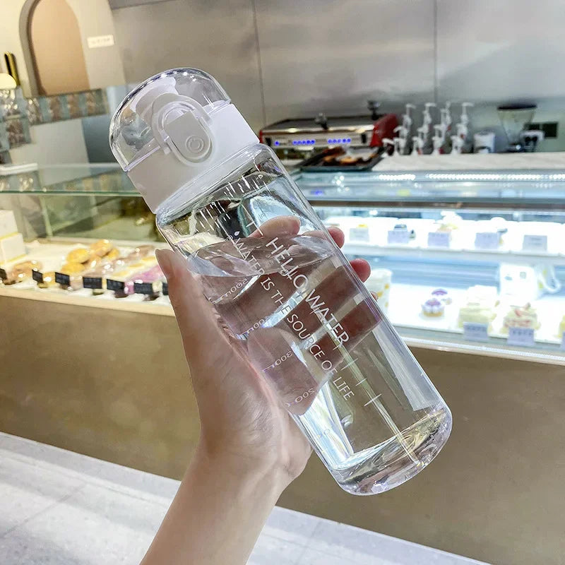 Clear water bottle held in a hand with a blurred bakery background