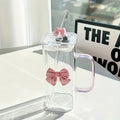 Clear glass mug with pink bow design on a white surface