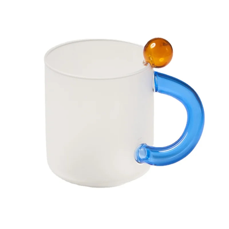 White mug with a blue handle and amber ball on a white background