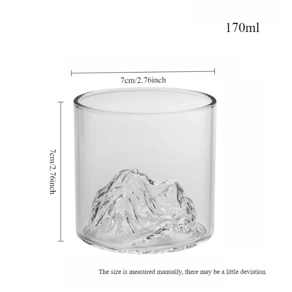 Clear glass tumbler with mountain design and measurements on a white background