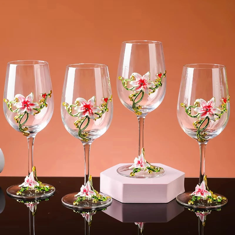 Four wine glasses with floral designs on a reflective surface and orange background