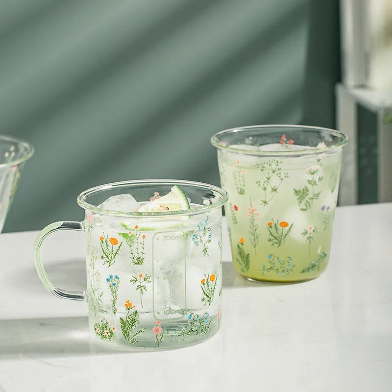 Two glass mugs with floral designs on a white surface.