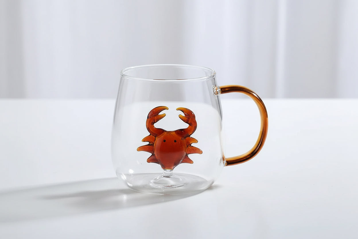 Clear glass mug with a brown crab design and handle on a white surface.