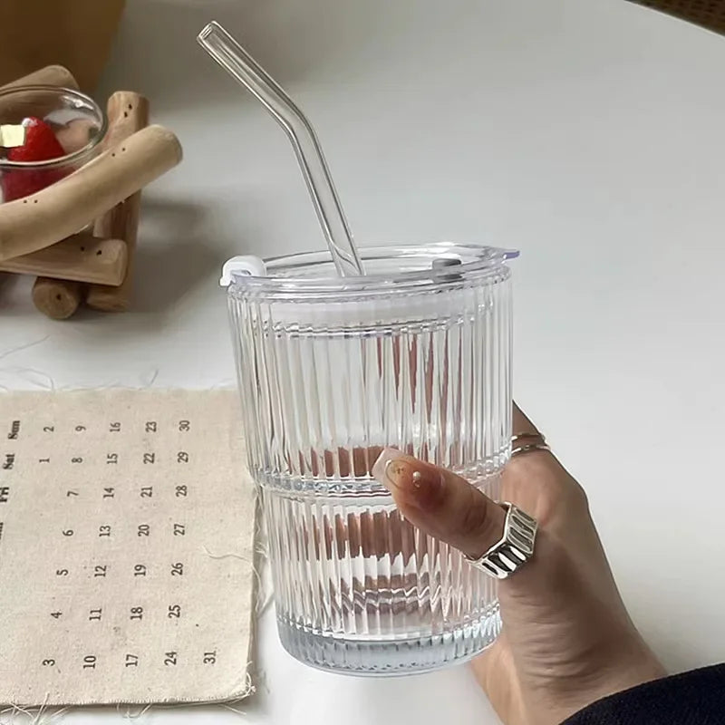 Clear glass with a straw held by a hand on a light surface with a calendar in the background