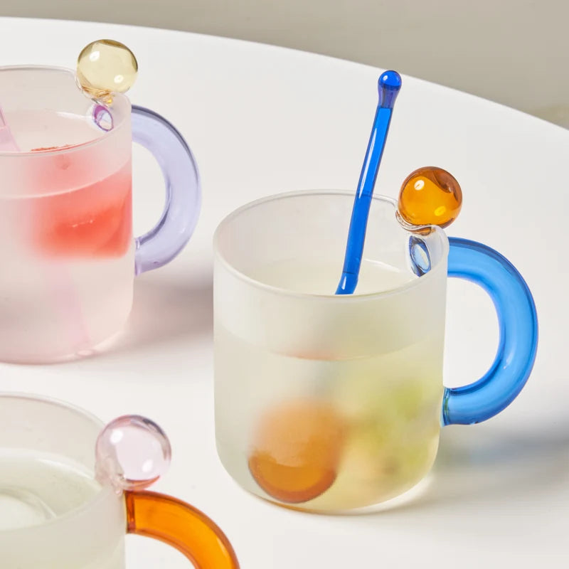 Colorful glass mugs with handle and colorful straws on a white background