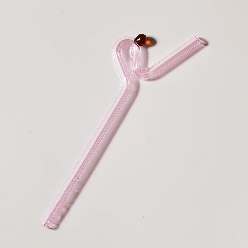Pink glass straw with a decorative element on a light gray background