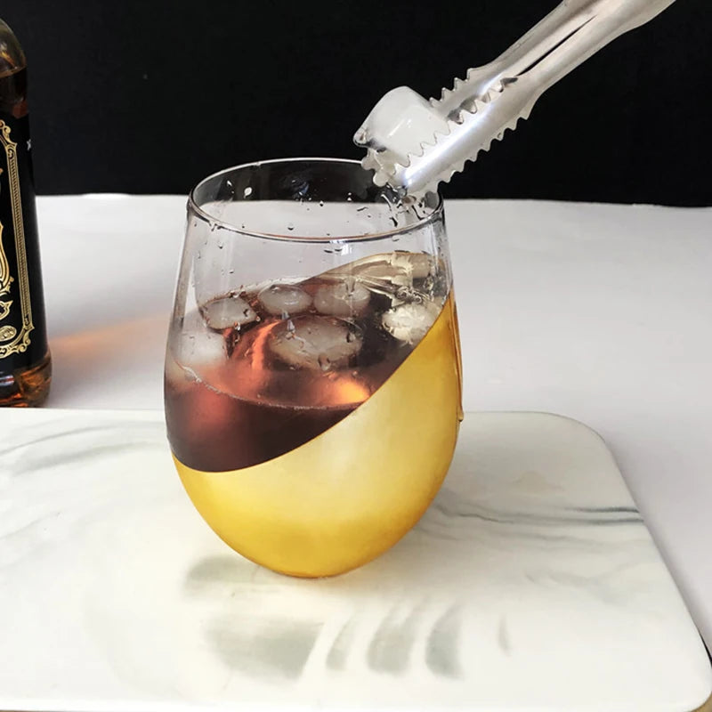 Glass with a layered drink and ice cubes, bottle in the background