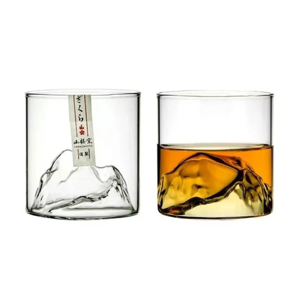Two glass tumblers with one filled with a amber liquid, on a white background.