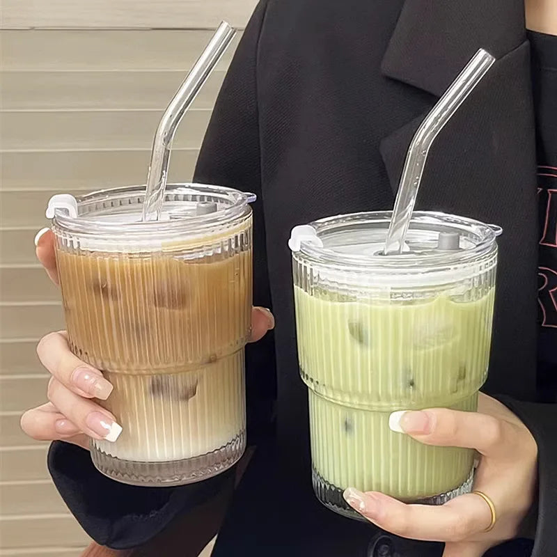 Two hands holding iced coffee and iced matcha in clear cups with straws.