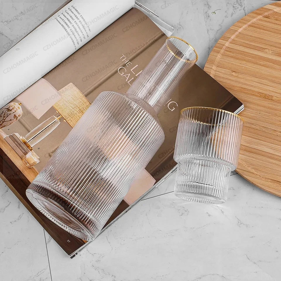 Two clear glass tumblers on a magazine with a wooden coaster in the background.