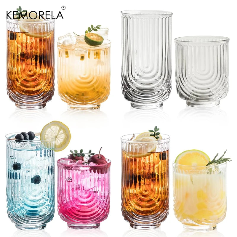 Set of colorful glass tumblers with drinks and garnishes on a white background, featuring the brand 'Kemorela'.