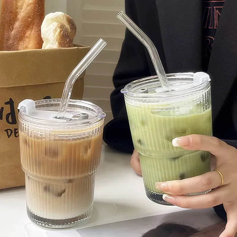 Two drinks in clear plastic cups with straws, one holding a green drink.