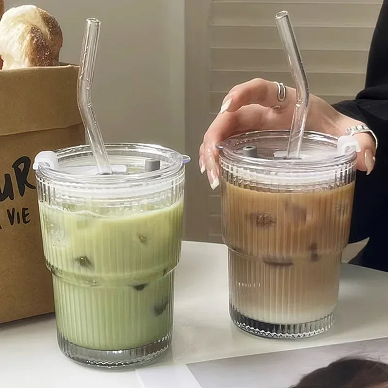 Two iced beverages in clear cups with straws, one green and one brown, on a white surface.