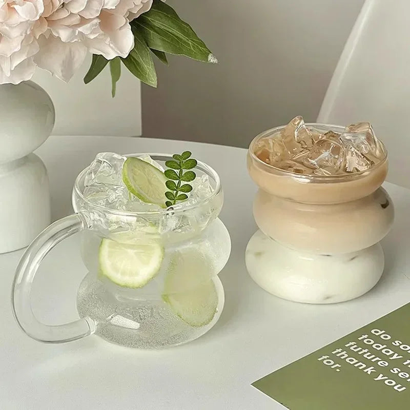Clear glass mug with ice and lime on a white surface with decorative elements.