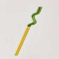 Green and yellow wavy straw on a light gray background