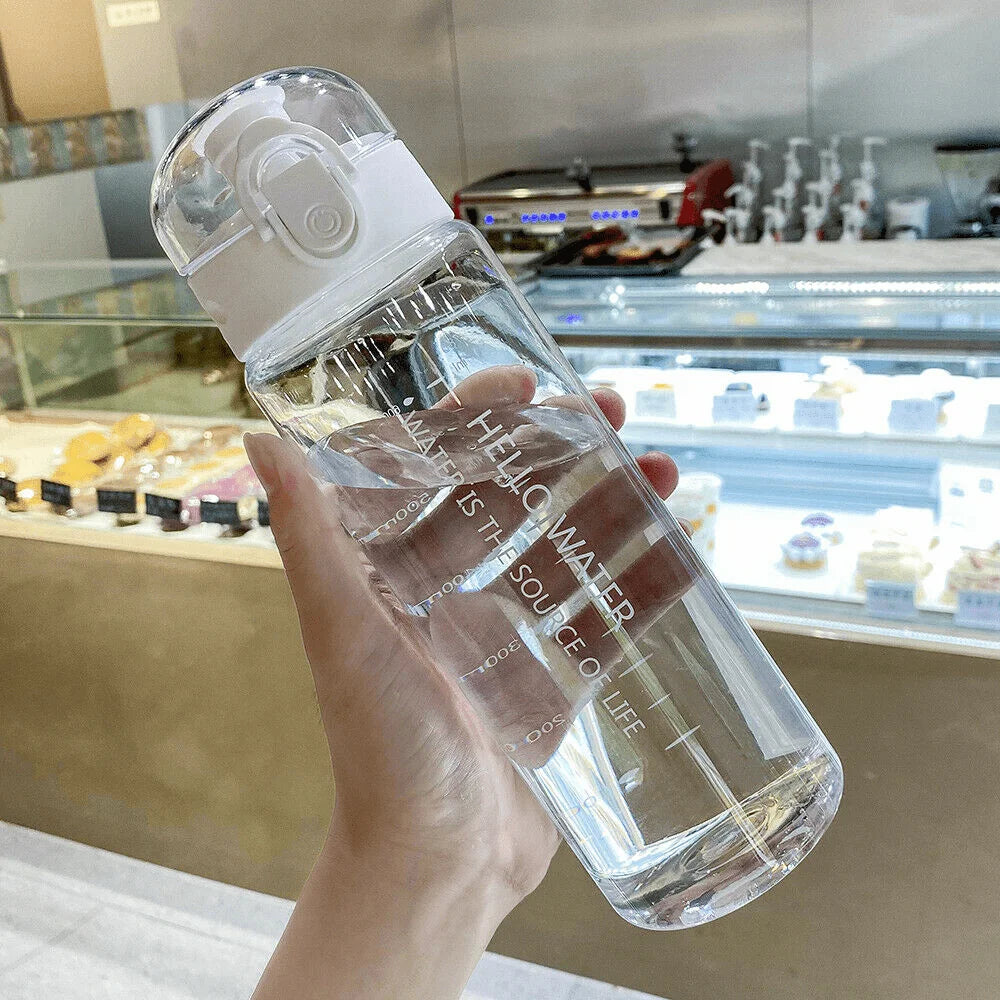 Clear water bottle held by a hand with a blurred background of a bakery.