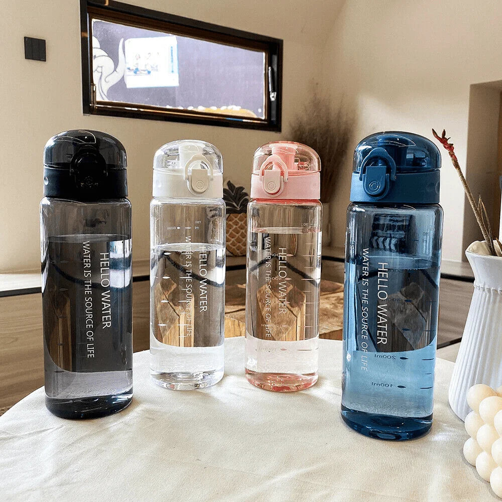 Four water bottles with different colored lids on a table.