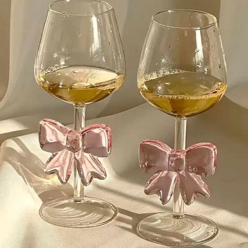 Two wine glasses with pink bow designs on a neutral background