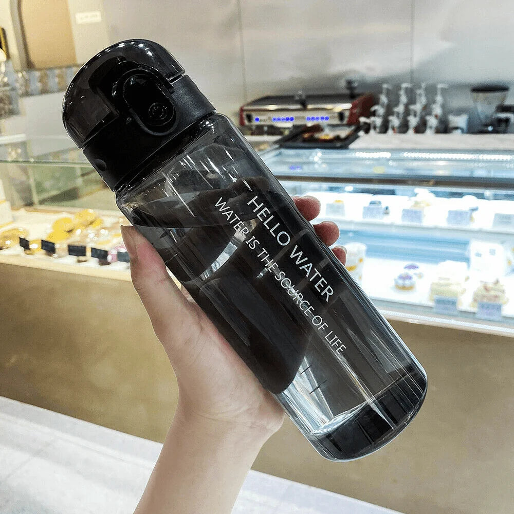 Clear water bottle with black lid held in a hand, blurred background of a store.