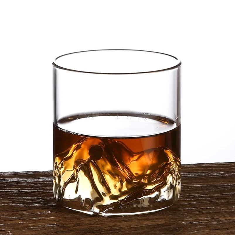 Glass of whiskey with ice cubes on a wooden surface