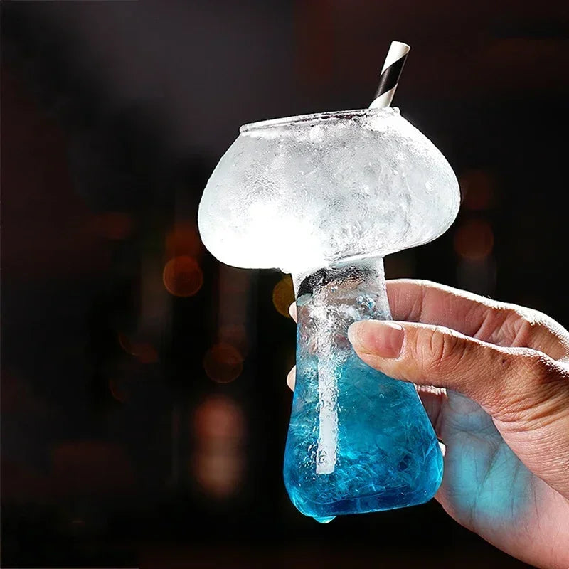Hand holding a frozen cocktail with a blue liquid and a straw against a dark background