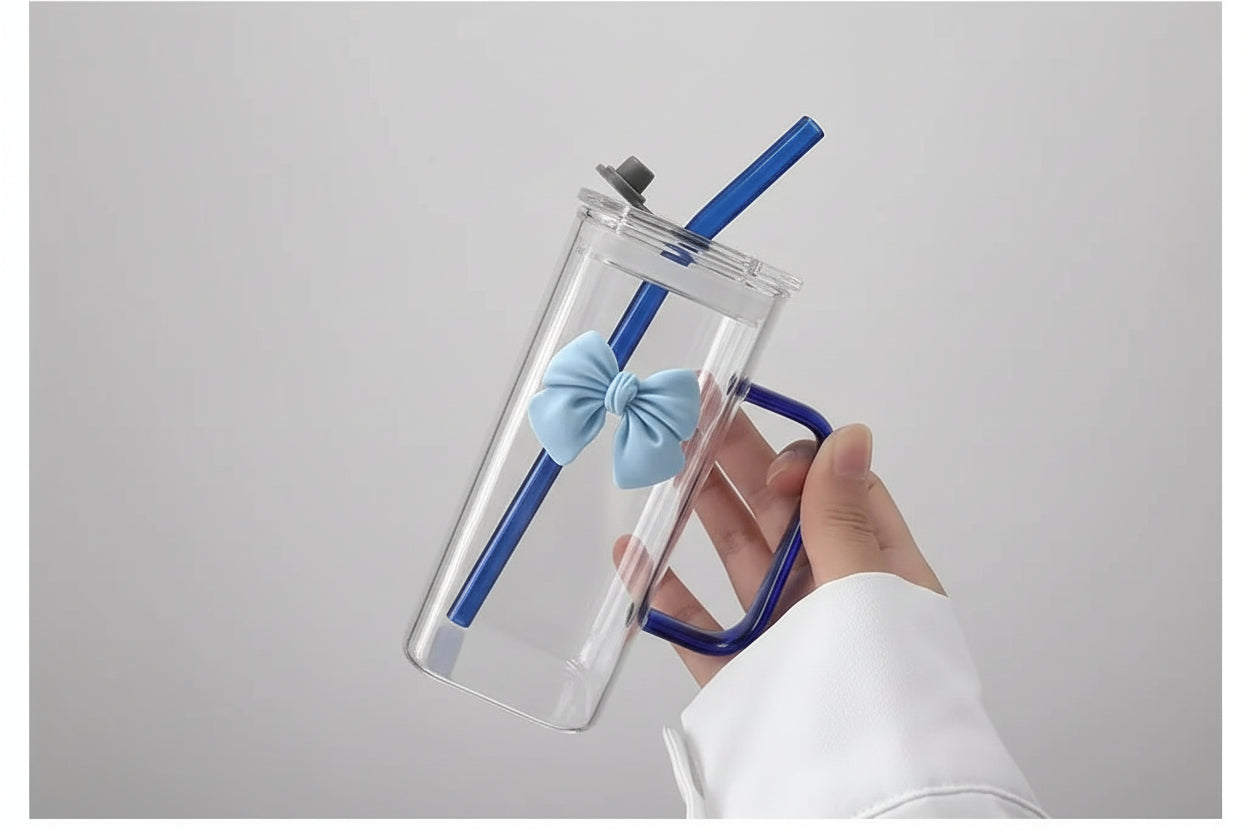 Clear glass tumbler with blue straw and bow tie held by a person indoors.