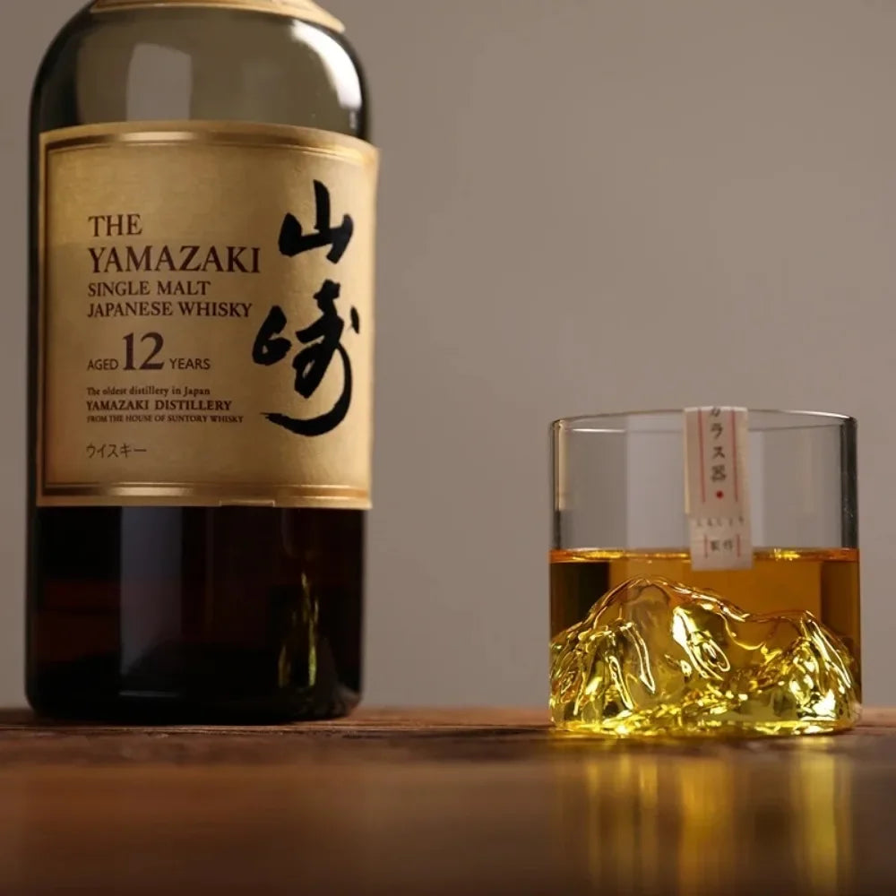 Yamazaki single malt Japanese whisky bottle with a glass of whisky on a wooden surface.