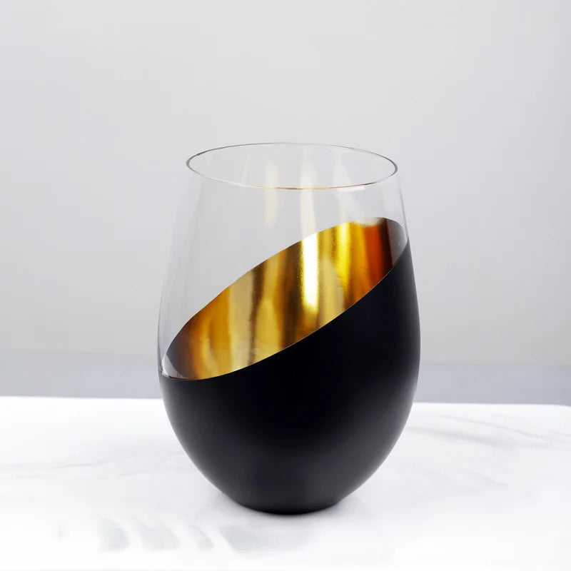 Black and gold wine glass on a white surface with a light gray background
