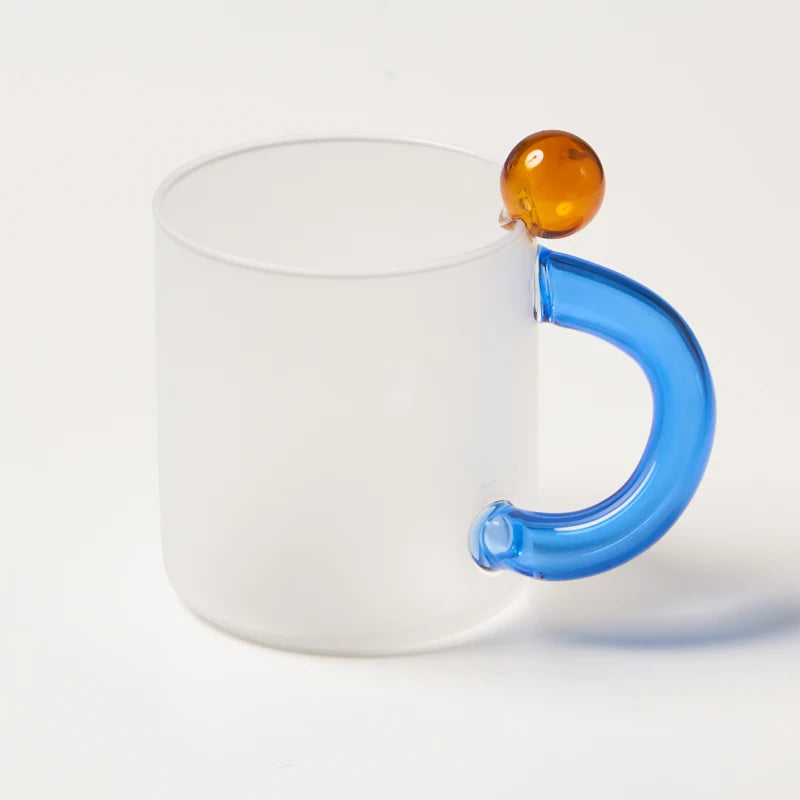 White mug with a blue handle and amber ball on a white background